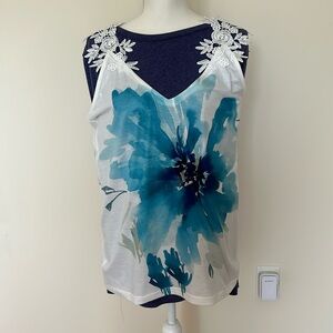 White tank top with blue flower on front and crocheted flower straps.